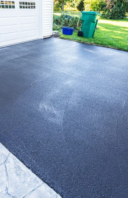 A residential asphalt driveway with a fresh coat of driveway sealant, providing a clean and protected finish.
