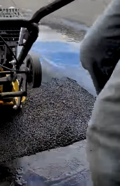 Close-up of a compactor finishing a patch during an asphalt driveway repair. Professional asphalt driveway paving requires high-pressure compaction for a durable finish.